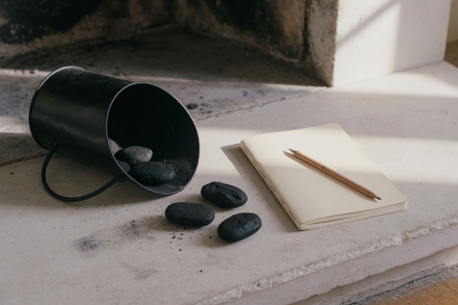 A coal scuttle and a notebook on a hearth